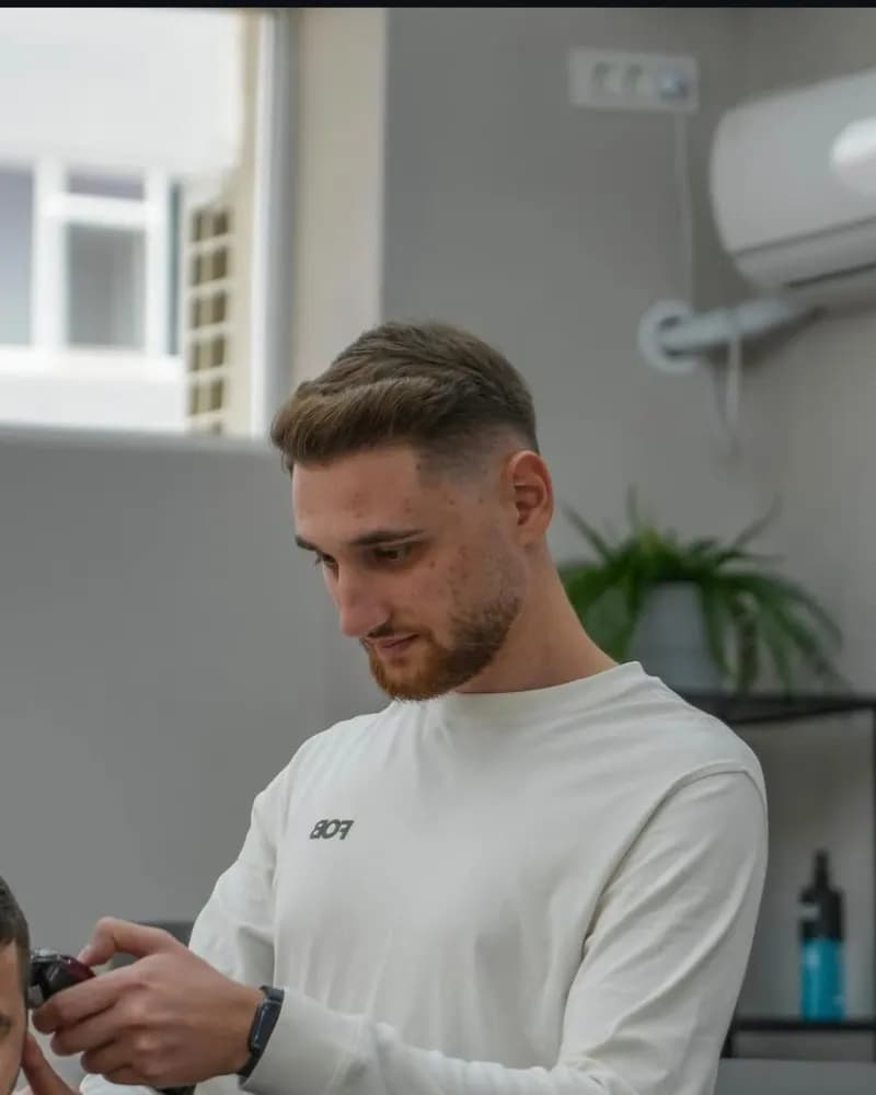 Cosmin Păunescu, frizer la R|B Barbershop, tunzând un client