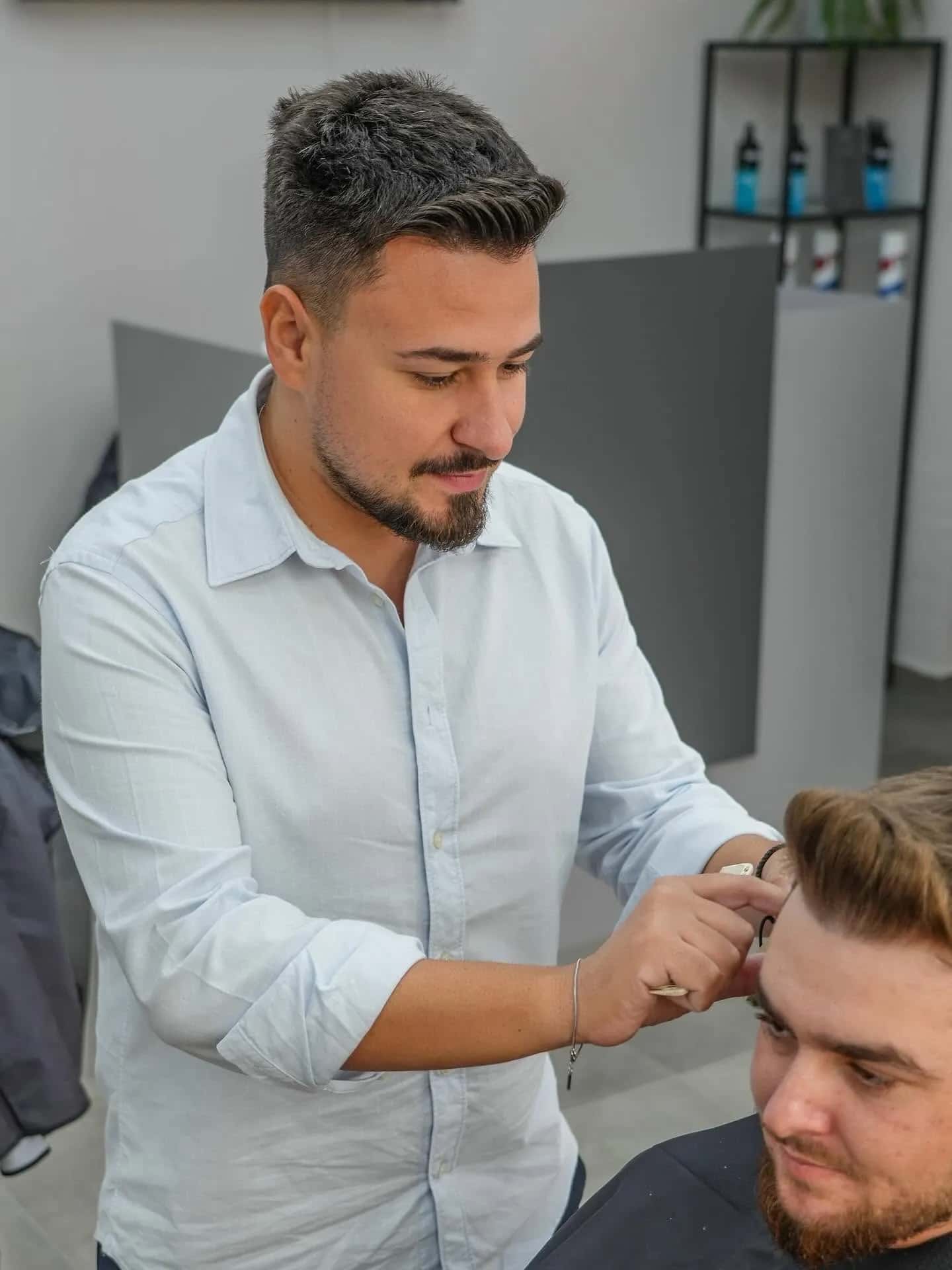 Frizer aranjând tunsoarea cu foarfeca la R|B Barbershop